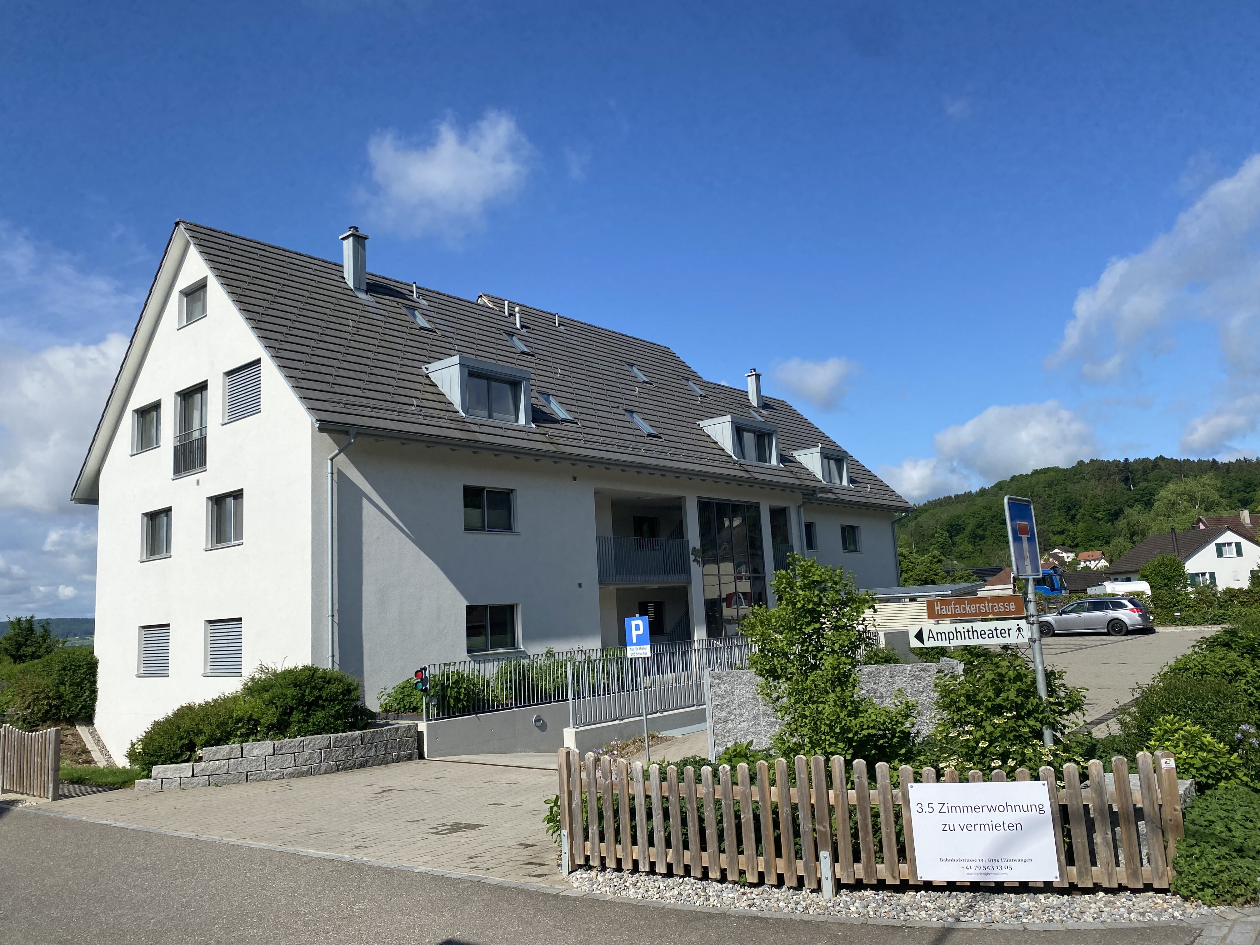 Weisses Mehrfamilienhaus mit Holz-Lattenzaun und Vorplatz in Hüntwangen